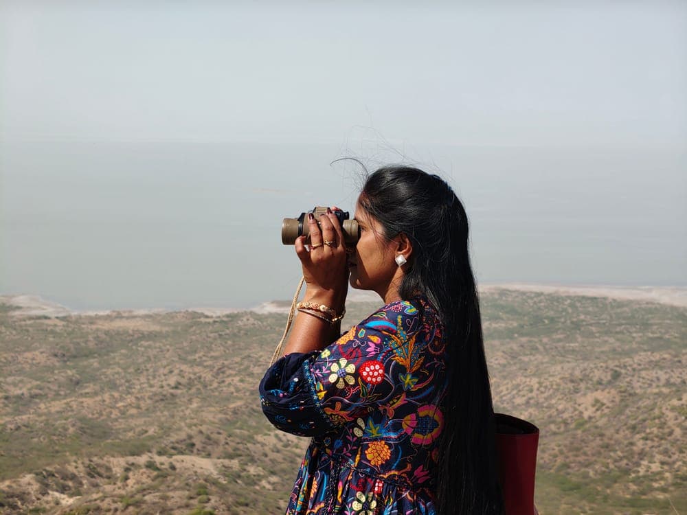 A woman looking through binoculars from a high point