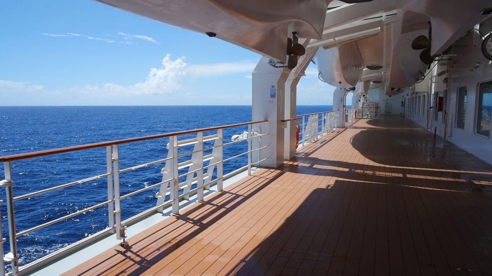 The open deck of a cruise ship with lifeboats and railings