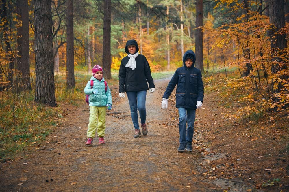 A mother and two children walking in an autumn forest