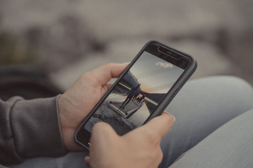 Hands holding a smartphone outdoors in the mountains