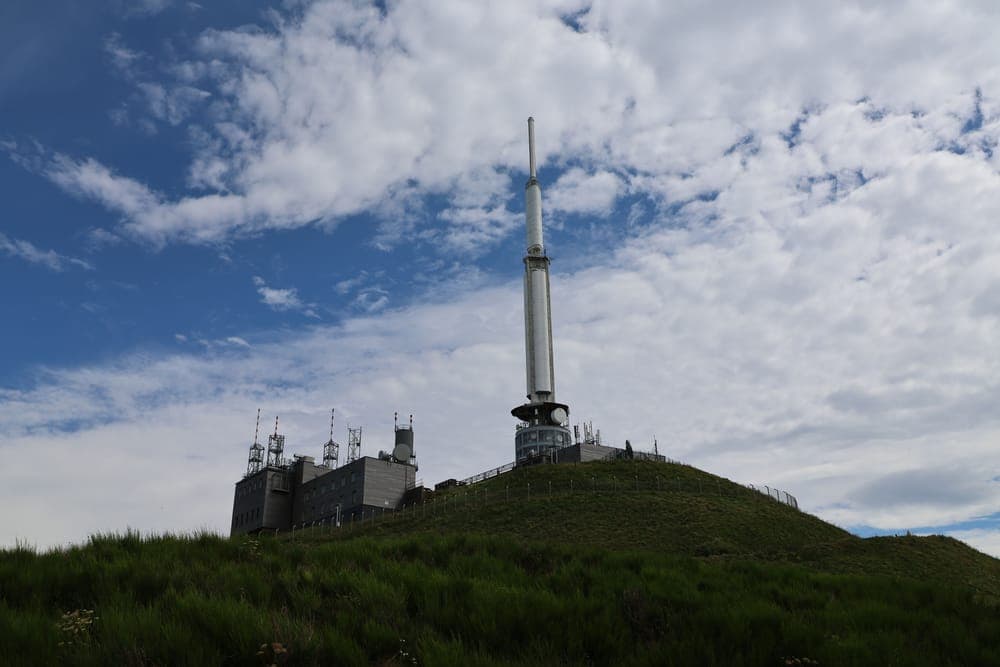 A communication tower on a green hilltop