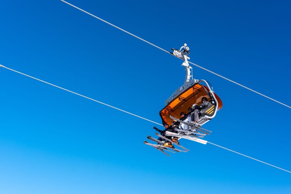 A chairlift carrying skiers under a clear blue sky