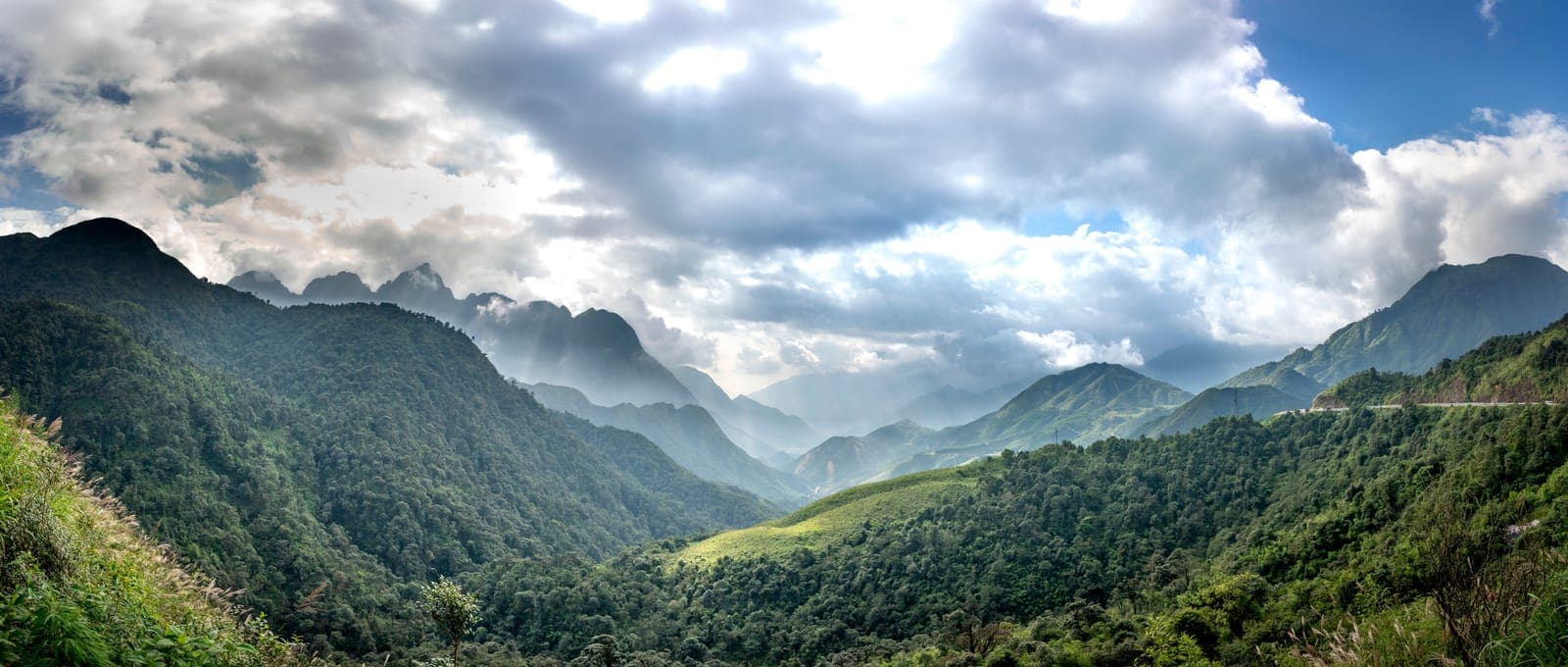Wide view of forested mountains and valleys under a glowing sky